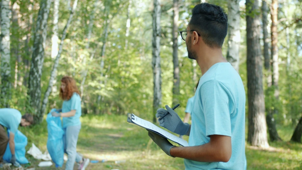Volunteers cleaning up a forest with trash bags.